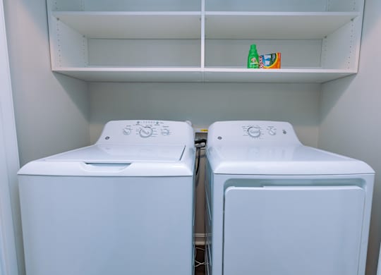 Two white washing machines in a laundry room.