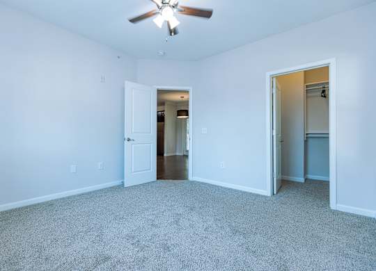 A room with a ceiling fan and carpeted floor.