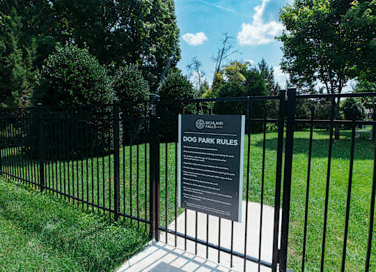 A sign in front of a fence that says Dog Park Rules.