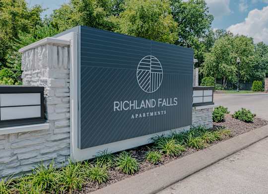 A sign for Richland Falls Apartments is shown in front of a building.