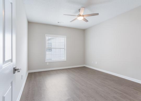 A room with a ceiling fan and a window with blinds.