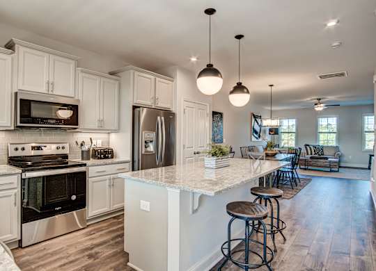 a kitchen with white cabinets and a large island with stools