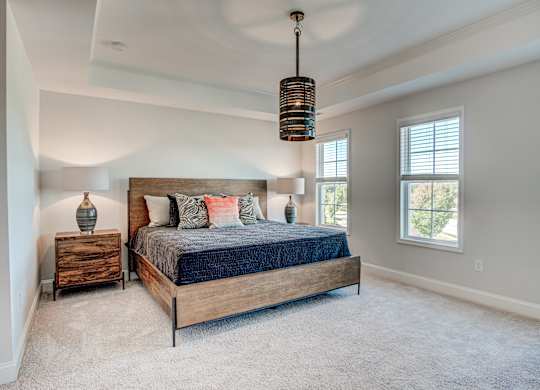a bedroom with a bed and two nightstands and a large window