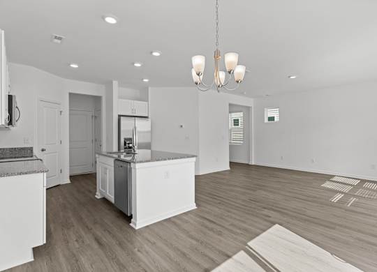 the living room and kitchen of a new home with white walls and wood flooring