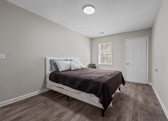 A bedroom with a bed, pillows, and a window.