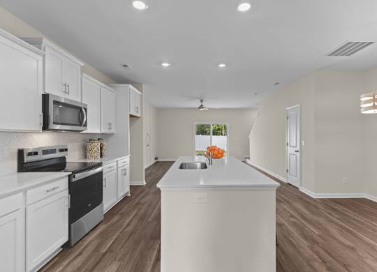 A kitchen with white cabinets and a white island.