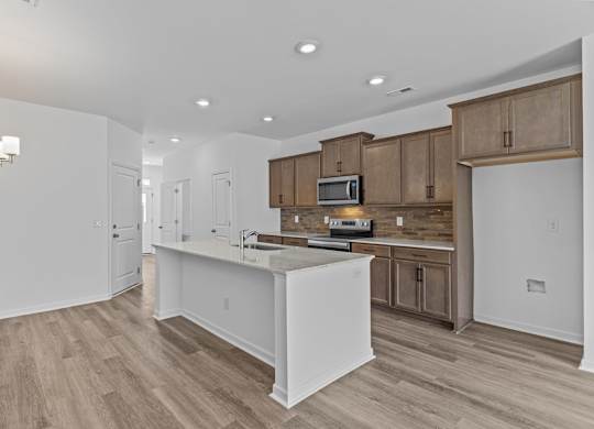 A kitchen with a white island and wooden cabinets.