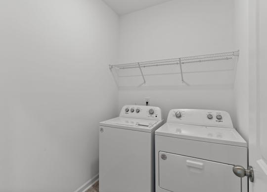 a white laundry room with two washes and a dryer