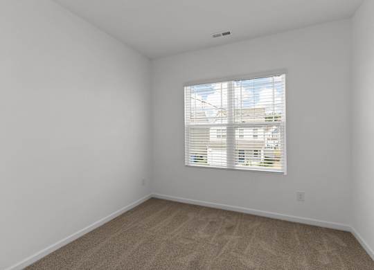an empty room with a window and white walls
