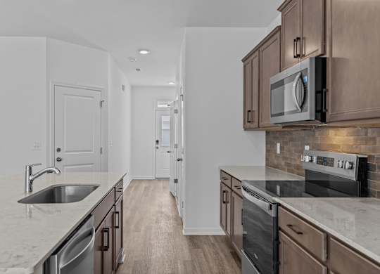 A kitchen with a sink, stove, and microwave.