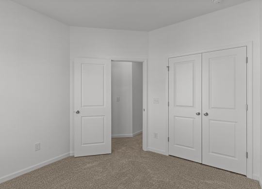 bedroom with white doors and white walls and carpeting and a closet