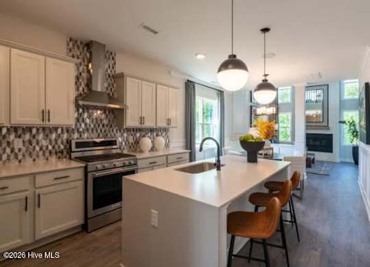 A kitchen with a white island and wooden chairs.