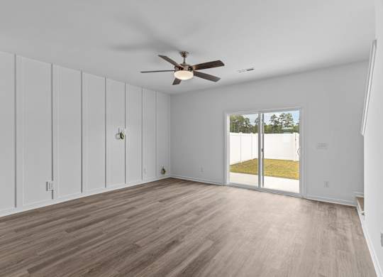 A room with a ceiling fan and sliding glass doors.