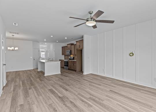 A room with a ceiling fan and wooden flooring.