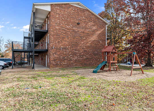 A red brick building with a playground in front.