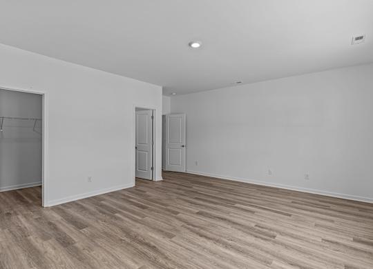 A room with white walls and wood flooring with two doors.