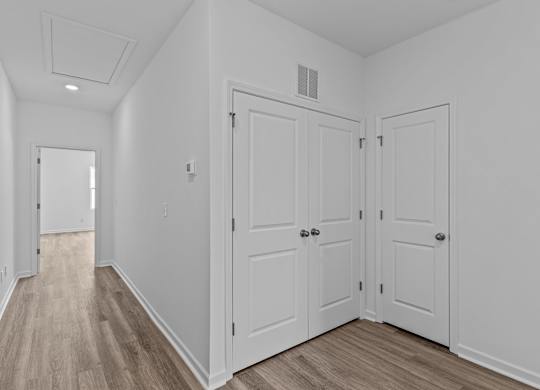 A hallway with two doors and a mirror on the wall.