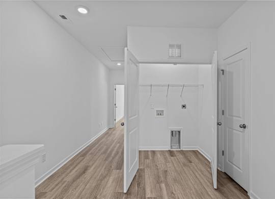 A white hallway with wood floors and a white door.