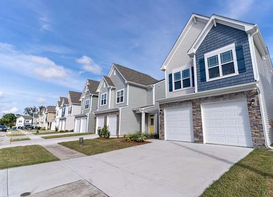 a row of houses with white doors and blue siding