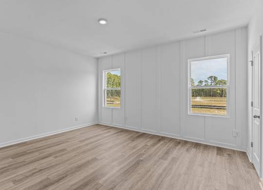 A room with white walls and a window showing a view of trees.