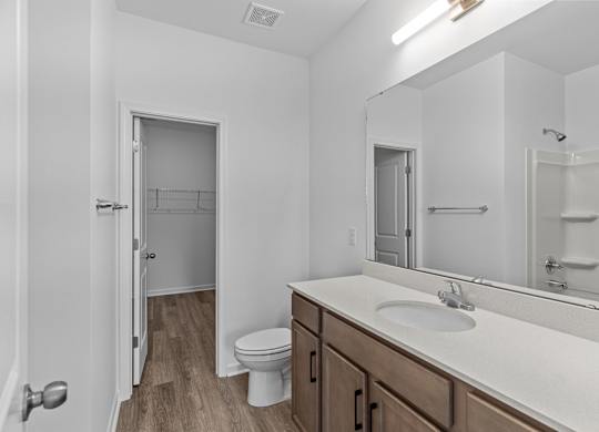 A white bathroom with a toilet, sink, and mirror.
