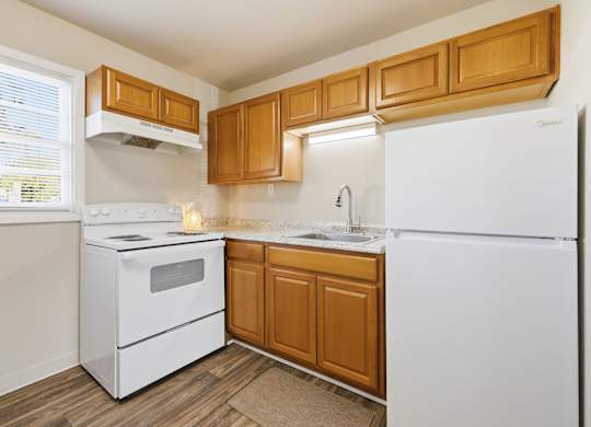 A kitchen with white appliances and wooden cabinets.