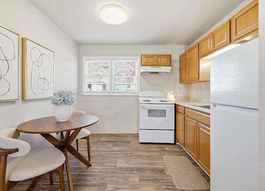 A kitchen with a white refrigerator, a white oven, and a brown table.