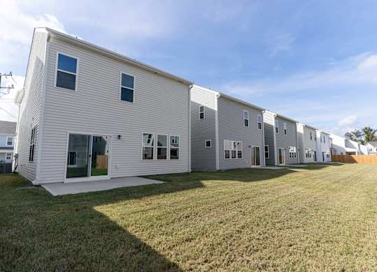 a row of white houses with a grassy yard