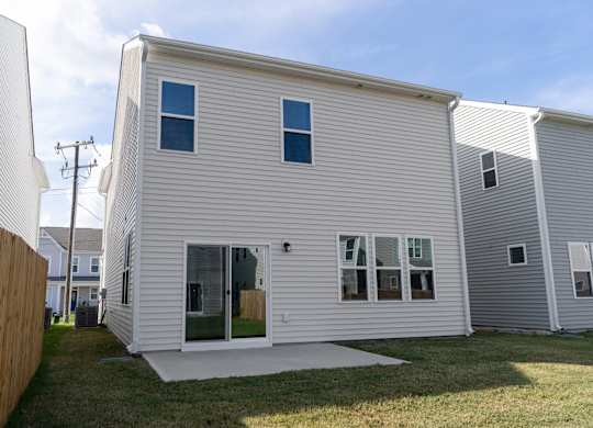 a white house with white siding and a patio in a yard