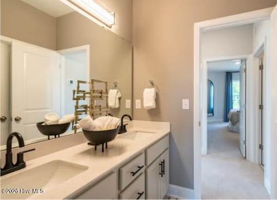 A bathroom with a sink, mirror, and a towel rack.