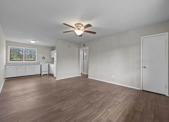 A room with a ceiling fan and wooden flooring.