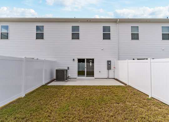A white house with a grey roof and a white fence.