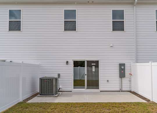 A white house with a grey fence and a grey air conditioner unit.