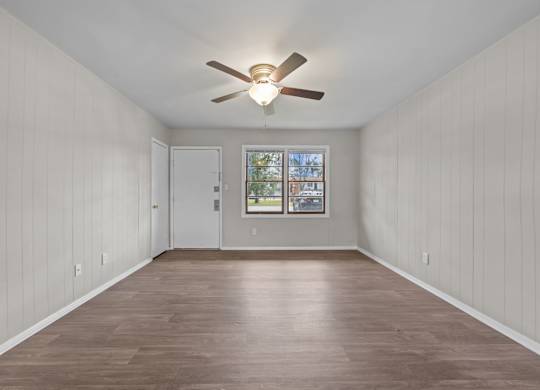 A room with a ceiling fan and wooden flooring.