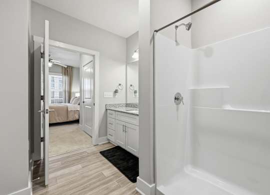 A white bathroom with a walk-in shower and a mirror.