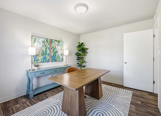 A room with a blue desk and a wooden table with a plant on it.