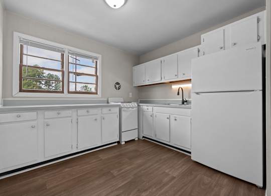 A kitchen with white cabinets and a window.