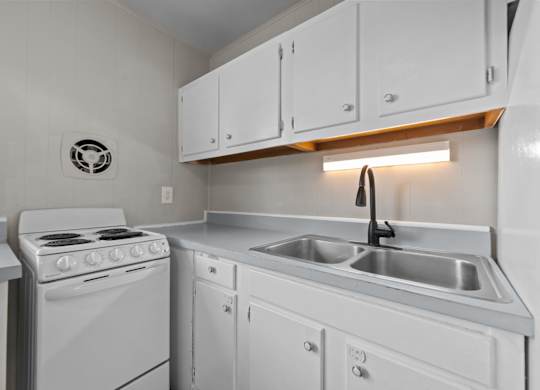 A white kitchen with a stove, sink, and cabinets.