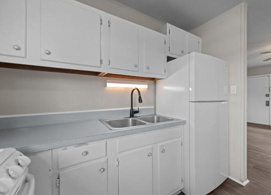 A kitchen with white cabinets and a white refrigerator.