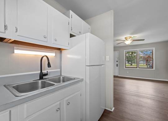 A kitchen with white cabinets and a stainless steel sink.