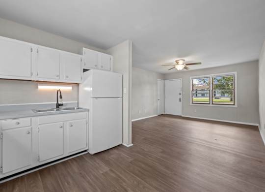 A kitchen with white cabinets and a wooden floor.