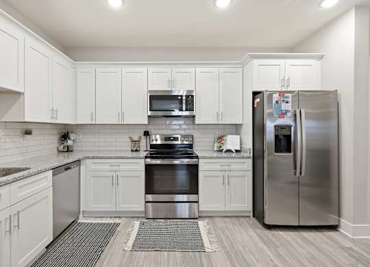 A modern kitchen with white cabinets and stainless steel appliances.
