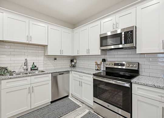 A kitchen with white cabinets and a black stove top oven.
