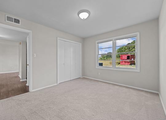 A room with a window showing a red building outside.