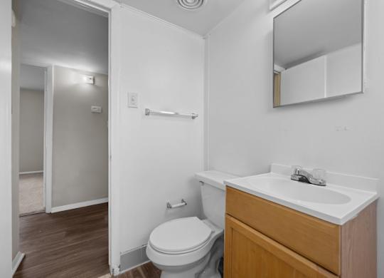 A white bathroom with a toilet, sink, and mirror.