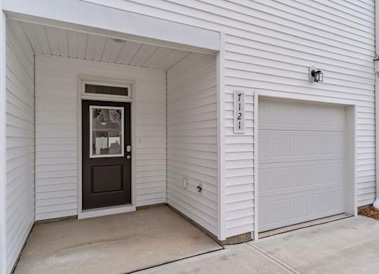 A white house with a black door and a garage door.