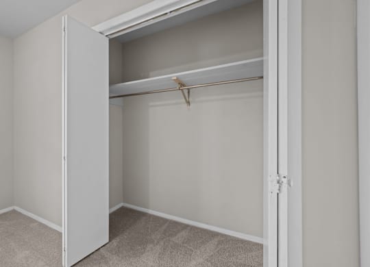 A white closet with a shelf and a white door.