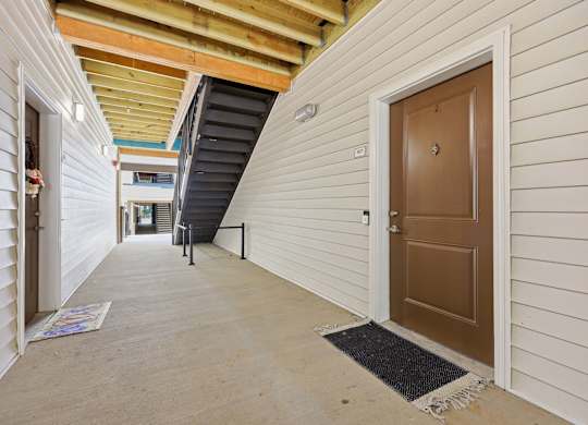 A hallway with a brown door and a black mat on the floor.