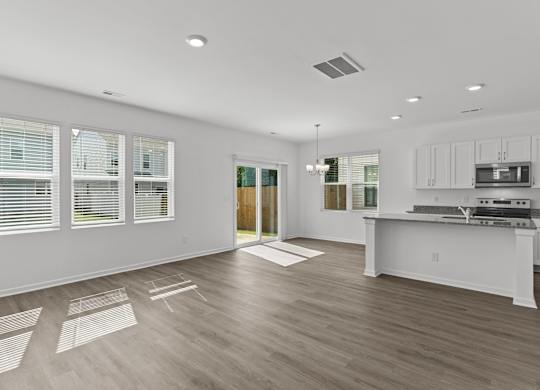the living room and kitchen of a new home with white walls and wood floors