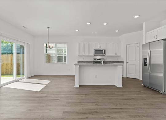 a white kitchen with stainless steel appliances and a door to a patio
